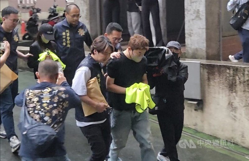 A man surnamed Huang (second right), suspected of operating a romance scam ring with his wife using AI voice-changing technology, is escorted by investigators after being arrested. CNA file photo